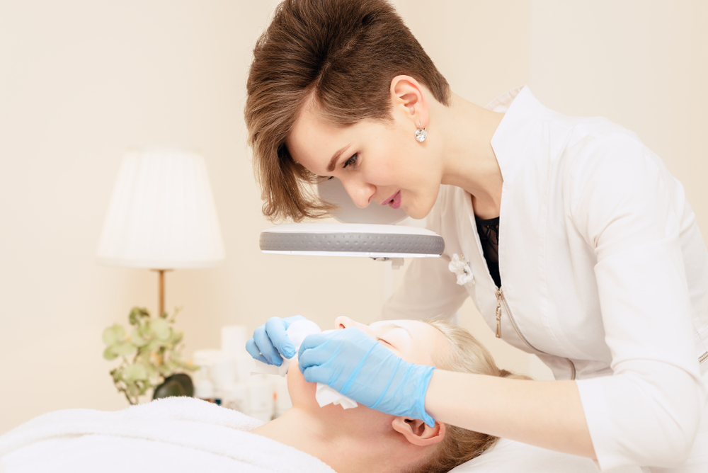 an esthetician applying facial treatment to client
