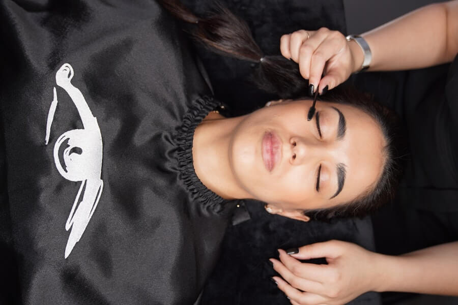 a woman having eyelash extensions applied by a lash technician
